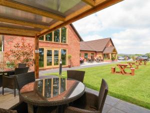 a patio with a table and chairs and a yard at Callow Lodge 22 in Hadnall