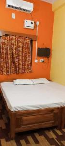 a bed in a room with an orange wall at OYO Flagship 81322 Laxmi Palace in Rourkela