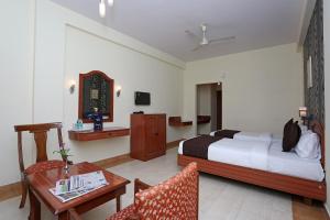 a hotel room with a bed and a table and chair at Super Collection O 9133 The Olive Star in Mysore