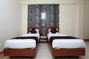 two twin beds in a room with a wall at Super Collection O 9133 The Olive Star in Mysore