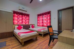 2 bedden in een kamer met rode gordijnen en een bureau bij OYO Flagship 1805 Hotel Star Delight in Pānchuria