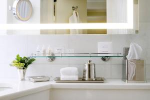 a bathroom with a sink, mirror, and soap dispenser at The Benjamin Royal Sonesta New York in New York
