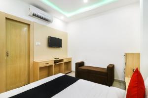 um quarto com uma cama e uma televisão na parede em Capital O 61009 Hotel Raj Mahal Sarnath em Varanasi