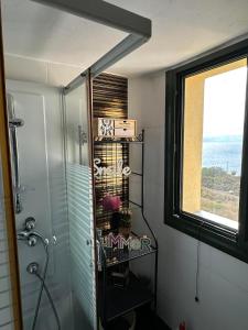 ein Bad mit einer Dusche, einem Fenster und einem Regal in der Unterkunft Sunset in Megalochori
