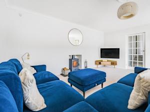 ein Wohnzimmer mit blauen Sofas und einem TV in der Unterkunft Fairwinds in Portreath