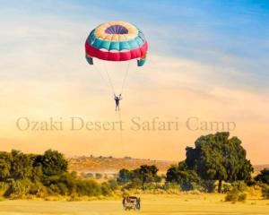 eine Person, die einen Fallschirm auf einem Feld fliegt in der Unterkunft Ozaki Desert Camp in Jaisalmer
