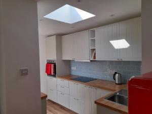 a kitchen with white cabinets and a skylight at Wisteria in St Austell