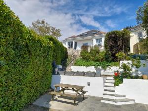 a wooden picnic table in front of a white house at Wisteria in St Austell