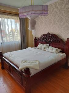 Schlafzimmer mit einem Holzbett mit Baldachin in der Unterkunft the heavenly apartments along Dennis prit road. in Nairobi