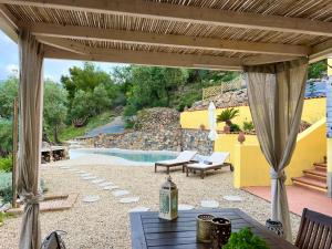 eine Terrasse mit einem Tisch, Stühlen und einem Pool in der Unterkunft Casale tra gli Ulivi in Diano San Pietro