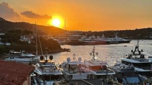 een groep boten aangemeerd in een jachthaven bij zonsondergang bij Porto Cervo Prestige in Porto Cervo