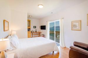 Habitación blanca con cama y balcón. en Cozy Oceanview! Hot Tub! Oceanfront! Shelter Cove, CA Tesla EV station, en Shelter Cove
