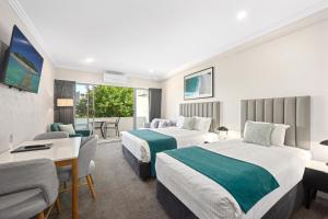 Una habitación de hotel con dos camas y balcón. en Palm Court Motor Inn, en Port Macquarie