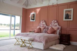 1 dormitorio con paredes rosas y 1 cama con silla en Finsbury House - Luxury 8 Bedroom Farm Homestead with Pool en Kilmore