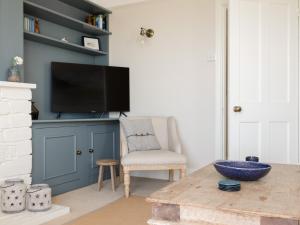 a living room with a tv and a chair and a table at Seascape in Salcombe