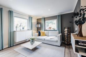 a living room with a white couch and two windows at Ferienwohnung "MeerTied" - Ankommen und Entspannen in Klausdorf Mecklenburg Vorpommern