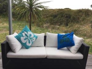 a couch with pillows sitting on a porch at Medlands Beach House in Great Barrier Island