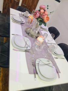 a table with white plates and a vase of flowers at Wohnung 51 in Oberwesel