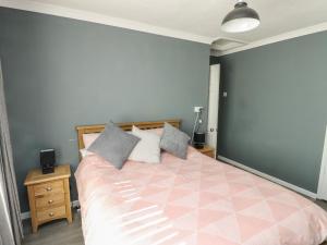 1 dormitorio con 1 cama grande con colcha rosa en 11 Bro Celyn, en Holyhead