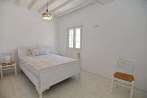 アノ・メラにあるMykonos 4 bedroom Cycladic home with free parkingの白いベッドルーム(ベッド1台、椅子付)