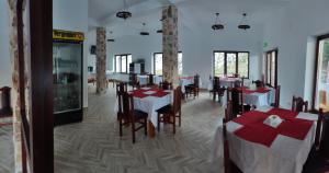 uma sala de jantar com mesas e cadeiras num restaurante em Pensiunea Trei Brazi Arieseni em Arieşeni