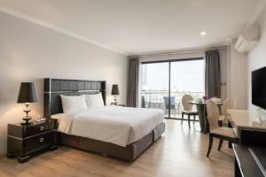ein Hotelzimmer mit einem Bett, einem Tisch und Stühlen in der Unterkunft Sirin Exclusive Hotel and Residence in Pattaya South