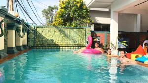 a group of children in a pool with a pink flamingo at THE PLACE Hostel & Pool Bar in Siem Reap
