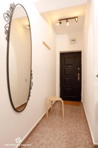 un grand miroir sur un mur dans un couloir avec un tabouret dans l'établissement Stylish Concept Studio, à Bucarest