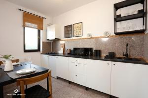 - une cuisine avec des placards blancs, un évier et une table dans l'établissement Stylish Concept Studio, à Bucarest