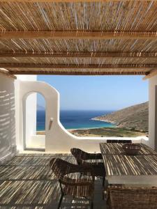 une terrasse avec des chaises et une table et une vue sur l'océan dans l'établissement Cyclades, villa surplombant la mer, à Ios Chora