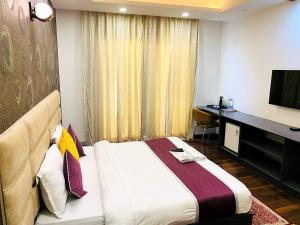um quarto de hotel com uma cama, uma secretária e uma televisão em Lime Tree Hotel Pulkit Gurgaon-Artemis Hospital, Nearest Metro Huda City Centre em Gurgaon