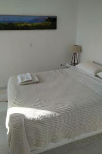 - un lit blanc dans une chambre blanche avec une photo sur le mur dans l'établissement Cyclades, villa surplombant la mer, à Ios Chora