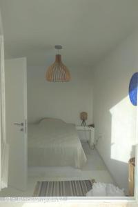 a white bedroom with a bed and a glass door at Cyclades, villa surplombant la mer in Ios Chora