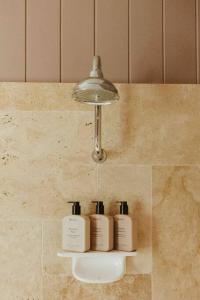 three shampoo bottles sitting on a shelf in a bathroom at Hinterland Luxury Stay - Eastnor in Montville