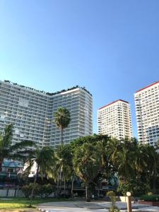 um edifício alto com palmeiras em frente em View Talay Condominium by Vlad Property em Pattaya Sul