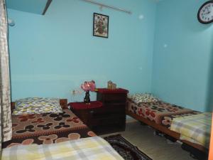 a bedroom with two beds and a dresser and a clock at Shanthi Villa in Coonoor