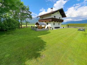 une maison sur un champ avec une grande pelouse dans l'établissement Haus Milan, à St. Johann in Tirol