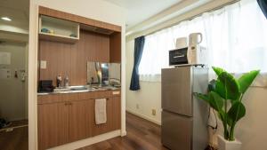 eine Küche mit einem Kühlschrank und einer Mikrowelle in der Unterkunft ELLE Namba 7 in Osaka