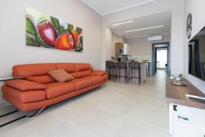 a living room with an orange couch and a kitchen at iitana Luxury Apartment - Catania Fronte Mare in Catania