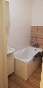 W łazience znajduje się biała wanna i umywalka. w obiekcie Kawalerka przy termach w mieście Poddębice