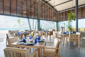 a restaurant with tables and chairs and the ocean at Madifushi Private Island in Meemu Atoll