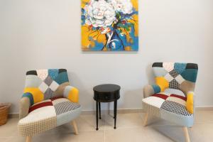 2 sillas y una mesa en una habitación con una pintura en iitana Luxury Apartment - Catania Fronte Mare en Catania