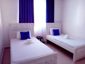 2 camas blancas con almohadas azules en una habitación en Lovely and spacious 3 bedroom apartment with swimming pool, en Mtwapa
