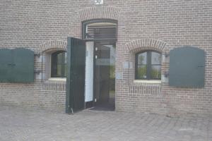 eine offene Tür eines Backsteingebäudes mit zwei Fenstern in der Unterkunft Bed & Breakfast Fort Bakkerskil in Nieuwendijk