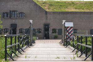 un ponte di legno di fronte a un edificio in mattoni di Bed & Breakfast Fort Bakkerskil a Nieuwendijk