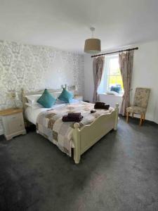 ein Schlafzimmer mit einem Bett mit blauen Kissen und einem Fenster in der Unterkunft Rokeby House, Reeth in Reeth
