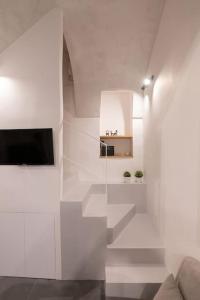a white living room with a tv and a couch at Casa Mirelli By Dimorra in Naples