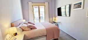 a bedroom with a bed with a window and a television at Malaga Lodge Apartments in Málaga