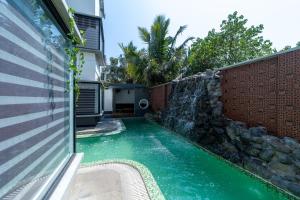 una piscina con cascada junto a una casa en Mermaid Farm House, en Pondicherry