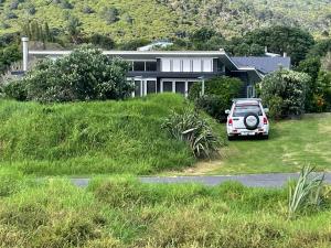 a white car parked in front of a house at Medlands Beach House in Great Barrier Island